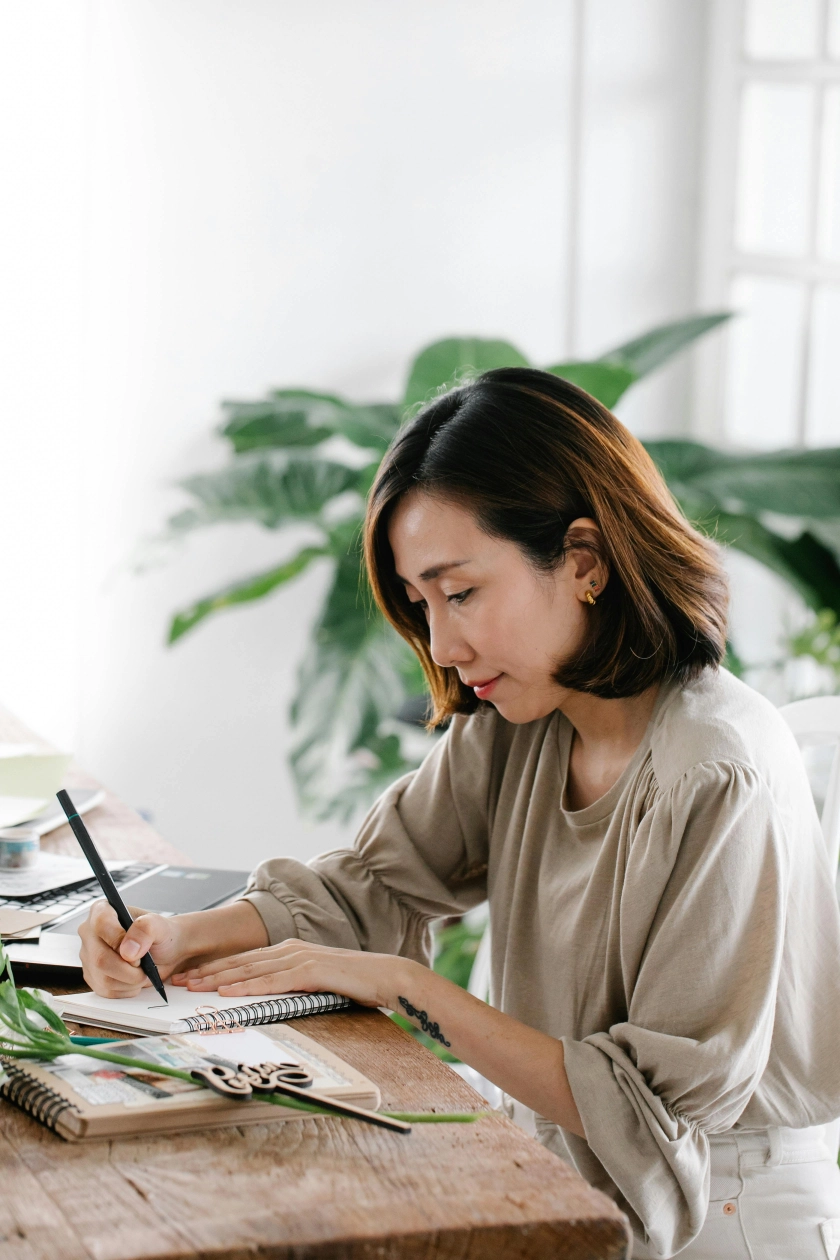 Focused woman writing in notebook, representing structured therapy and journaling as part of OCD treatment in Orange County